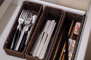 Un cajón con compartimentos que contiene cubiertos y palillos.