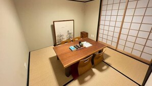 Ein traditioneller japanischer Raum mit Tatami-Bodenbelag, einem Holztisch und einem Shoji-Bildschirm.