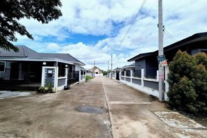 A residential street with houses, a clear sky, and a few puddles on the road. - We House - Hangdong 2 (Hang Dong)