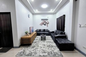 A modern living room with a sectional sofa, a wooden side table, and a gray rug. - We House - Hangdong 2 (Hang Dong)