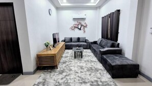 A modern living room with a sectional sofa, a wooden console table, a small coffee table, and a decorative wall piece. - We House - Hangdong 2 (Hang Dong)