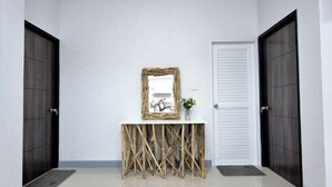 A hallway with a white console table, a mirror, and a framed picture. There are two dark wooden doors on either side. - We House - Hangdong 2 (Hang Dong)