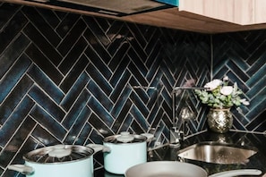 A kitchen with a black herringbone tile backsplash, a stainless steel sink, and a vase with flowers on the counter. - INARA VILLA , Luxury Pool Villa Pattaya by Viola & Olivia (Pattaya)