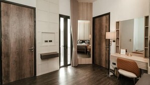 A modern hotel room with a wooden floor, a large mirror, a vanity with a lamp, and a cushioned chair. - INARA VILLA , Luxury Pool Villa Pattaya by Viola & Olivia (Pattaya)