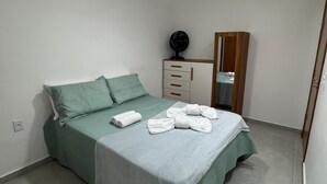 Et soveværelse med en seng, en loftventilator, et sengebord med en ventilator og et spejl.