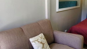 Ein beiges Sofa mit einem gemusterten Kissen in einem Raum, mit einer blaugrünen Polsterbank an der Wand.