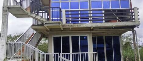 Un edificio de varios pisos con un balcón, una escalera y una fachada amplia con ventanas.