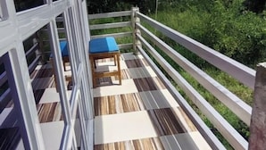 Ein Balkon mit Schachbrettmuster-Boden, weißem Geländer und einem blauen Kissen.