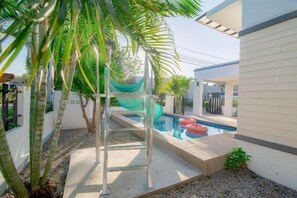A swimming pool with a slide, surrounded by palm trees and a white building. - Sweet Hua-Hin Private Pool Villa from beach 3 km (Hua Hin)