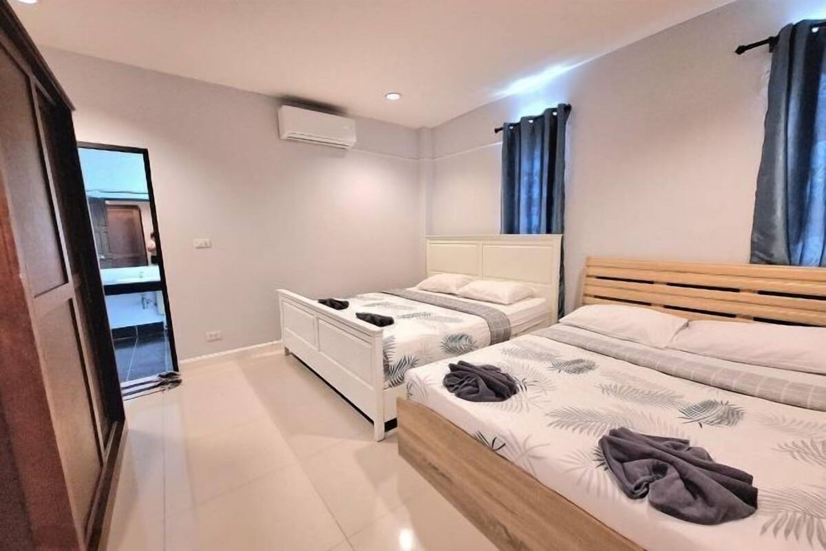 A modern bedroom with two beds, a wardrobe, and a mirror.