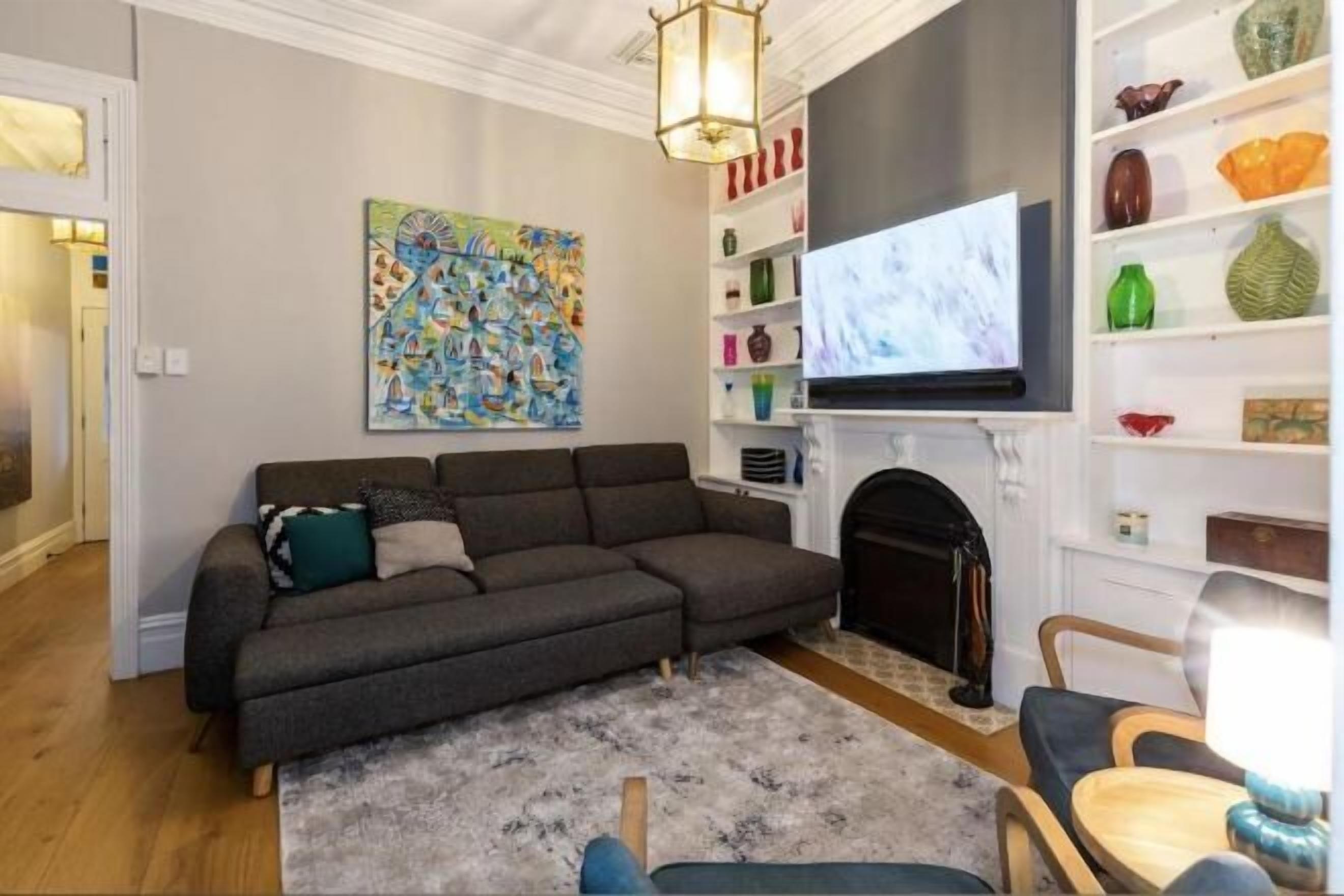 Una sala de estar con un sofá modular, una chimenea, un televisor y una estantería.