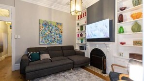 A living room with a sectional sofa, a fireplace, a television, and a bookshelf. - Millers Point Home Harbourside (Millers Point)