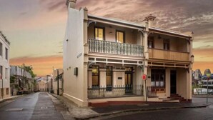 A two-story building with a balcony on the upper floor, a front porch, and a street view. - Millers Point Home Harbourside (Millers Point)