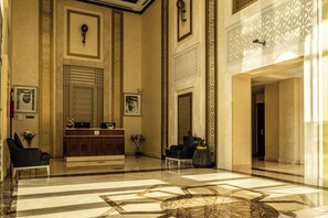 A lobby with a reception desk, seating area, and decorative wall patterns. - Suha Al Jaddaf (Dubai)