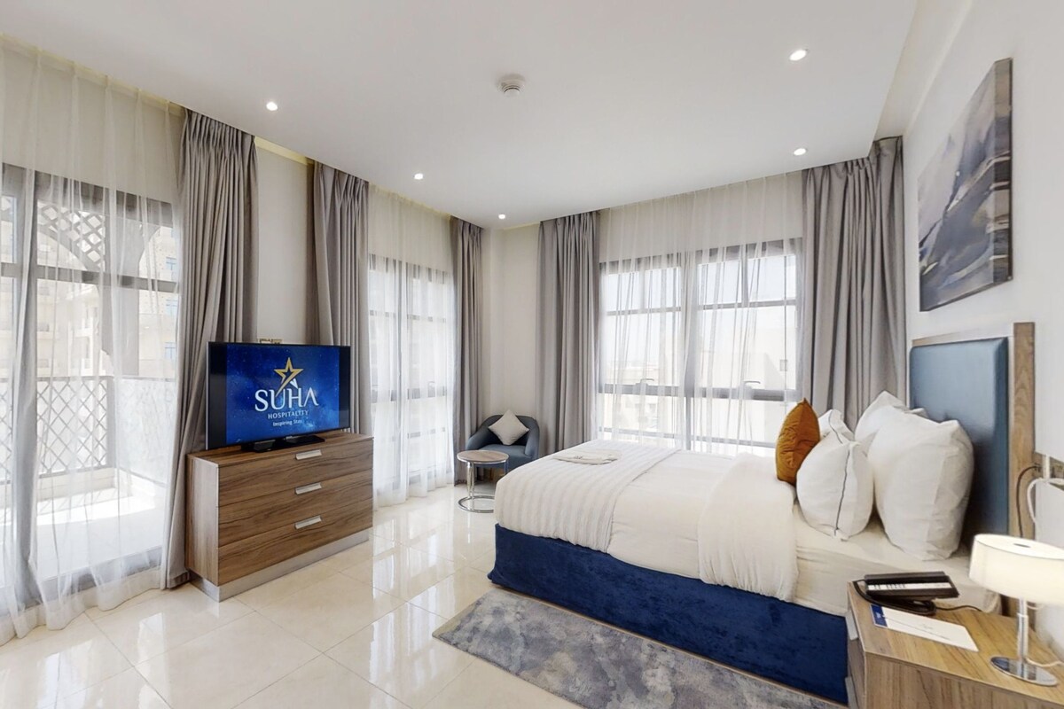 Une chambre d’hôtel moderne équipée d’un grand lit, d’une télévision et d’un bureau avec une lampe.