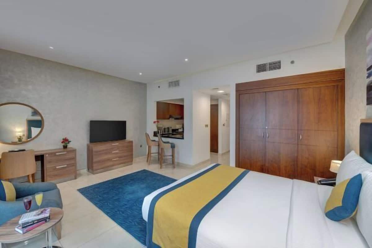 Une chambre d’hôtel moderne équipée d’un lit, d’un bureau, d’une télévision et d’une armoire.