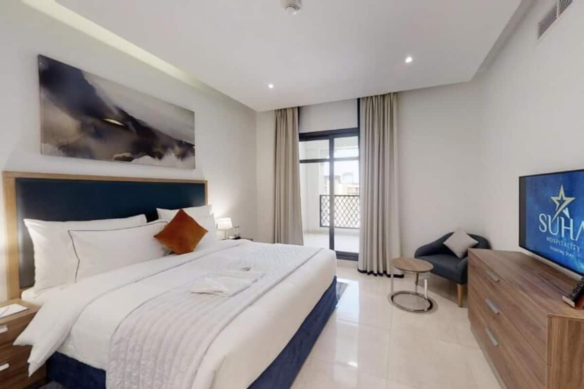 Une chambre d’hôtel moderne dotée d’un grand lit, d’une télévision, d’un bureau et offrant une vue sur la ville.