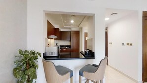 A modern kitchen with a central island, two bar stools, and a potted plant.