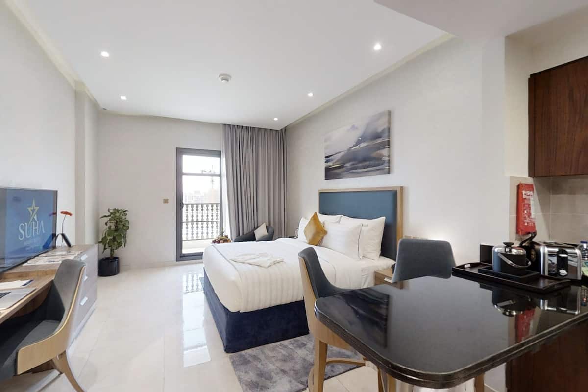 Une chambre d’hôtel moderne équipée d’un lit, d’un bureau, d’une chaise et d’une kitchenette.