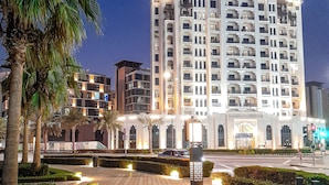 A multi-story hotel with a prominent star sign on the roof, a paved walkway, and palm trees.