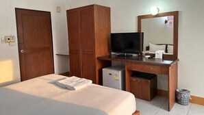 Una camera d'albergo con un letto, un armadio in legno, una scrivania con televisore e un piccolo frigorifero.