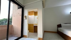 Una camera da letto con un letto, una porta scorrevole che dà su un bagno e un balcone.
