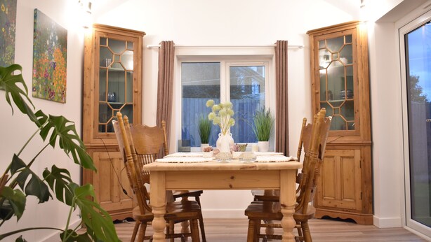 Ein Essbereich mit einem Holztisch, Stühlen und einem Fenster mit Vorhängen.