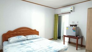 A bedroom with a bed, a TV on a stand, and an air conditioning unit. - Khunnampheung Apartment (Sakon Nakhon)