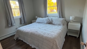 Una camera da letto con un letto grande, due comodini e una finestra con tende.