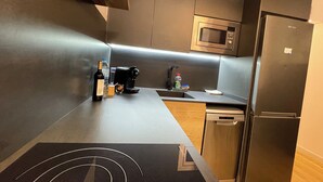 Een moderne keuken met een ingebouwde magnetron, een koelkast, een koffiezetapparaat en een spoelbak.