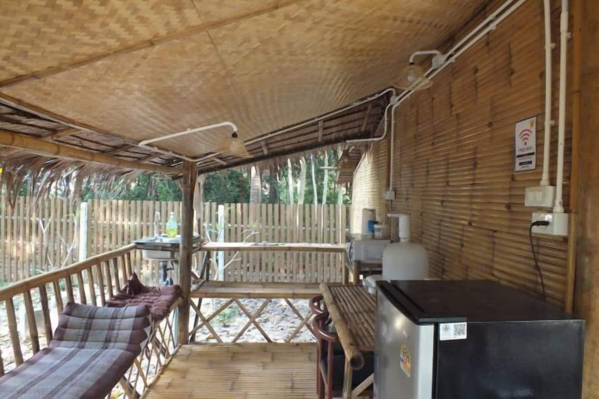 Un espacio al aire libre techado con un banco de madera, una mesa y un refrigerador.