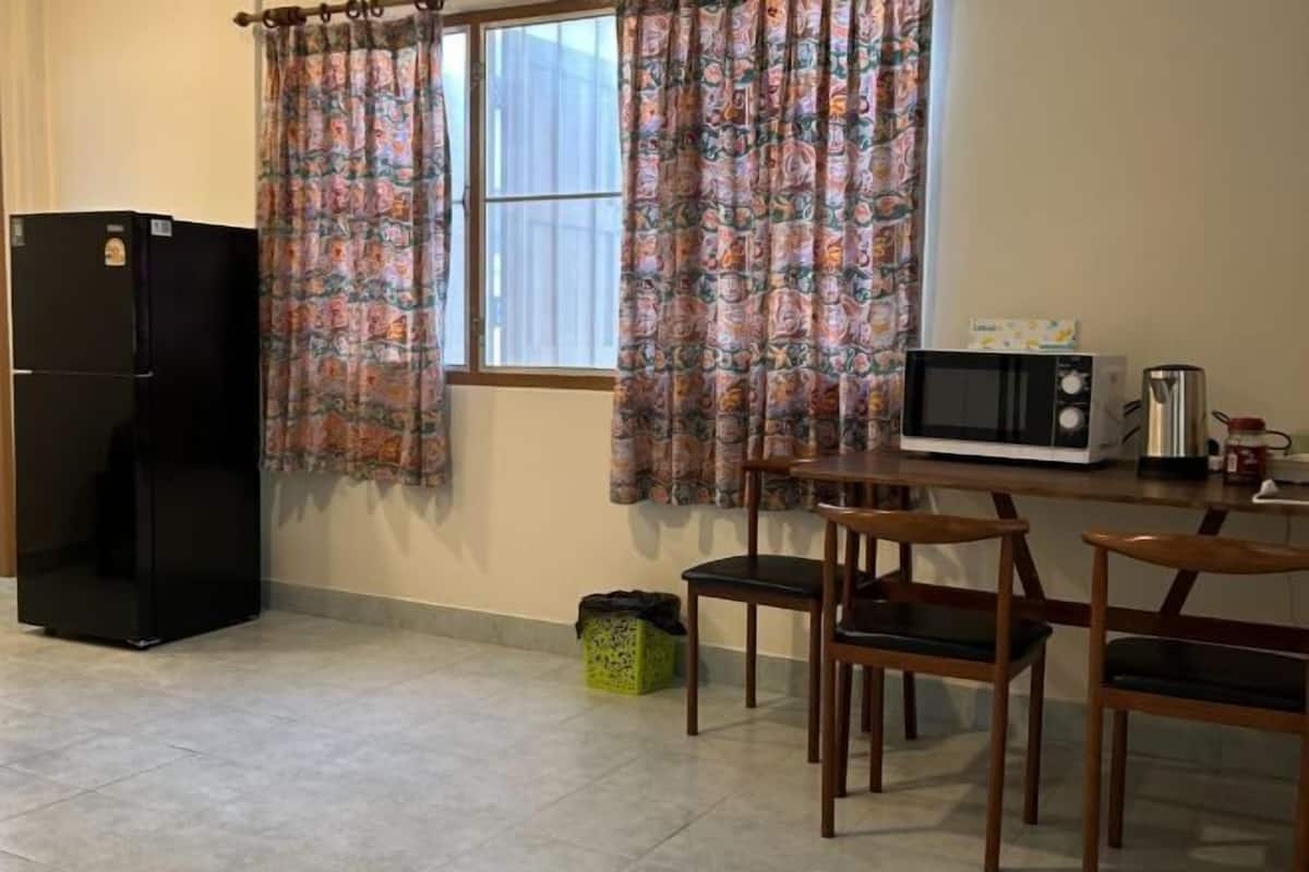 Una cocina compacta con refrigerador, microondas y una pequeña mesa de comedor con sillas.