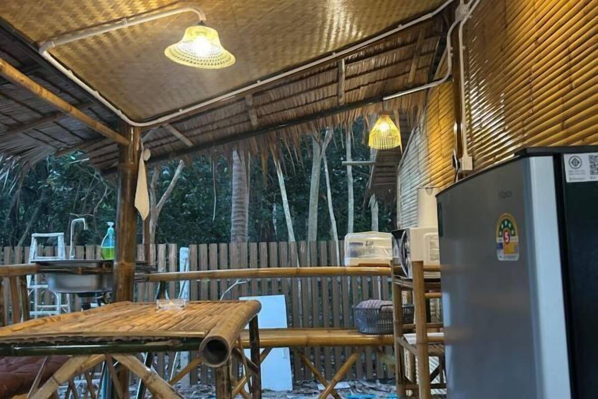 Un espacio al aire libre techado con una mesa, luces colgantes y un refrigerador.