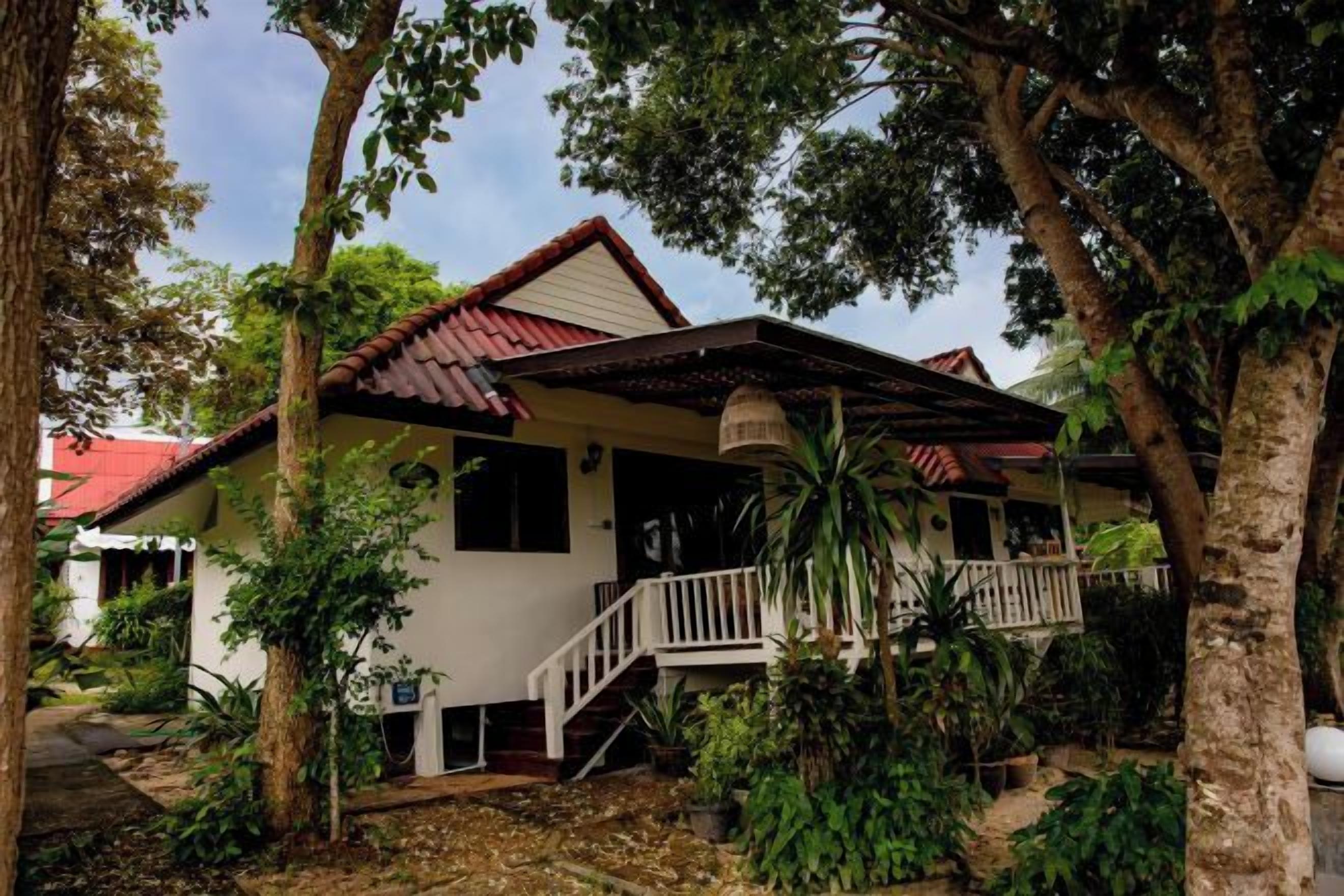 A two-story house with a porch, surrounded by trees.