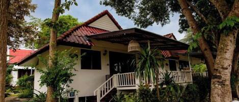 A two-story house with a porch, surrounded by trees.