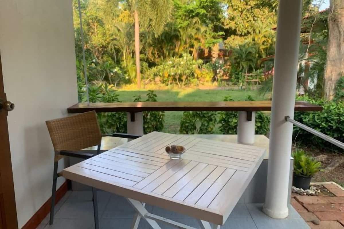 Un balcón con mesa y sillas, con vistas a un jardín exuberante.