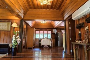 Un interior de madera con chimenea, una zona de comedor y un pasillo que conduce a una puerta.