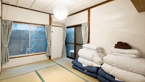 A traditional Japanese room with tatami flooring, a futon bed, sliding doors, and a view of a snowy landscape. - 8 min by train from Ikebukuro Station, 18 min from Shinjuku Station (Tokyo)
