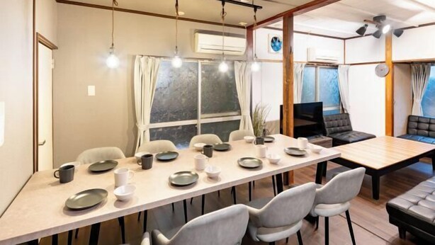 A dining area with a long table, chairs, and a TV screen. - 8 min by train from Ikebukuro Station, 18 min from Shinjuku Station (Tokyo)