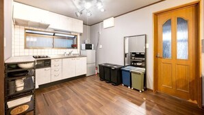 A compact kitchen with white cabinets, a microwave, and a wooden door. - 8 min by train from Ikebukuro Station, 18 min from Shinjuku Station (Tokyo)