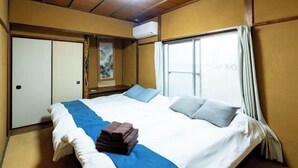 A hotel room with a large bed, a wardrobe, a window with curtains, and an air conditioning unit. - 8 min by train from Ikebukuro Station, 18 min from Shinjuku Station (Tokyo)