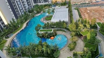 A swimming pool surrounded by greenery, adjacent to high-rise buildings.