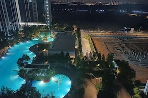Una piscina rodeada de vegetación y edificios, con vista a una obra en construcción al fondo.