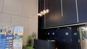 A reception area with a black reception desk, a poster advertising property investment, and a plant.