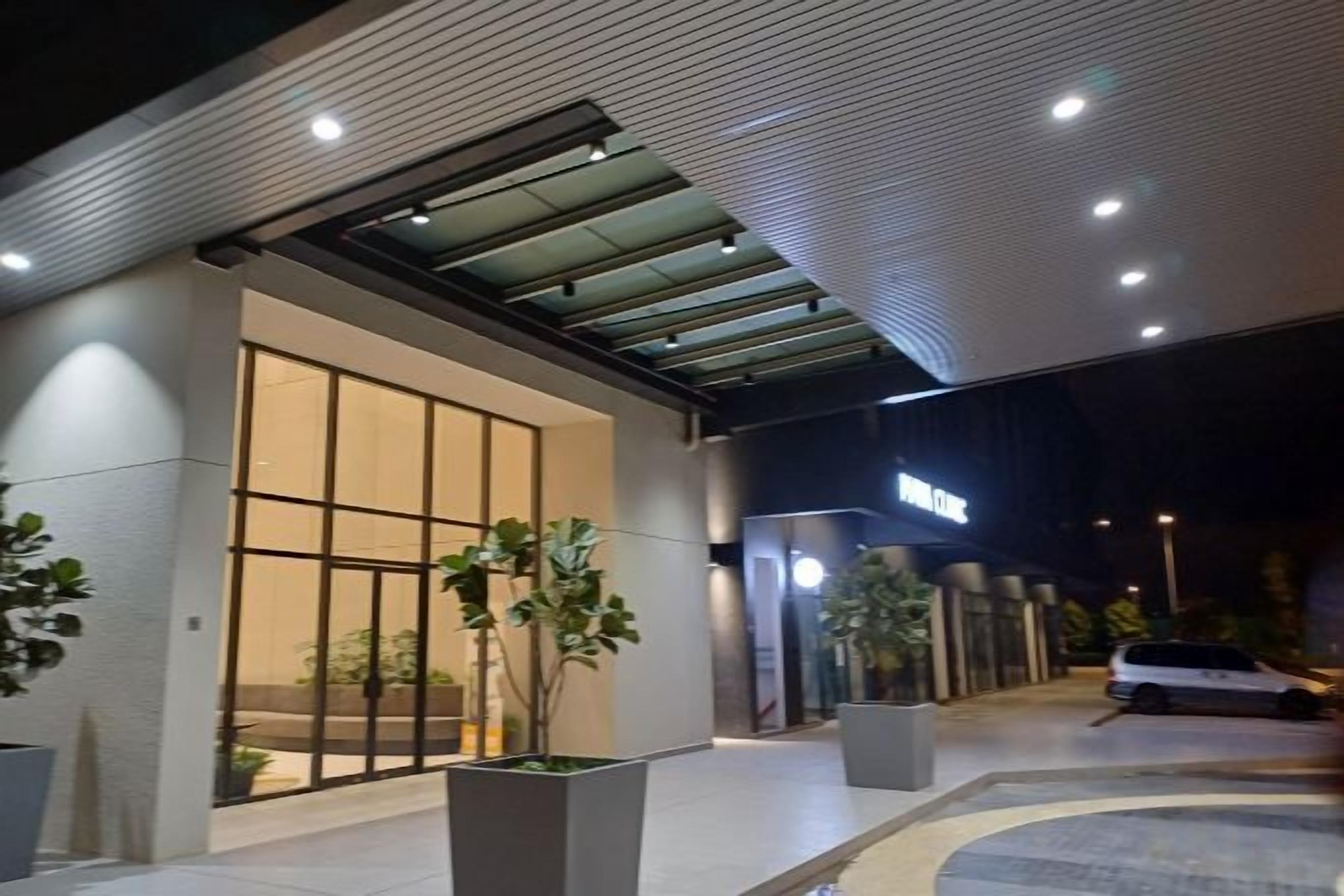 A hotel entrance with a glass door, potted plants, and a sign above the door.