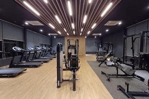 Ein Fitnessstudio mit LaufbÀndern, KraftgerÀten und einer Spiegelwand.