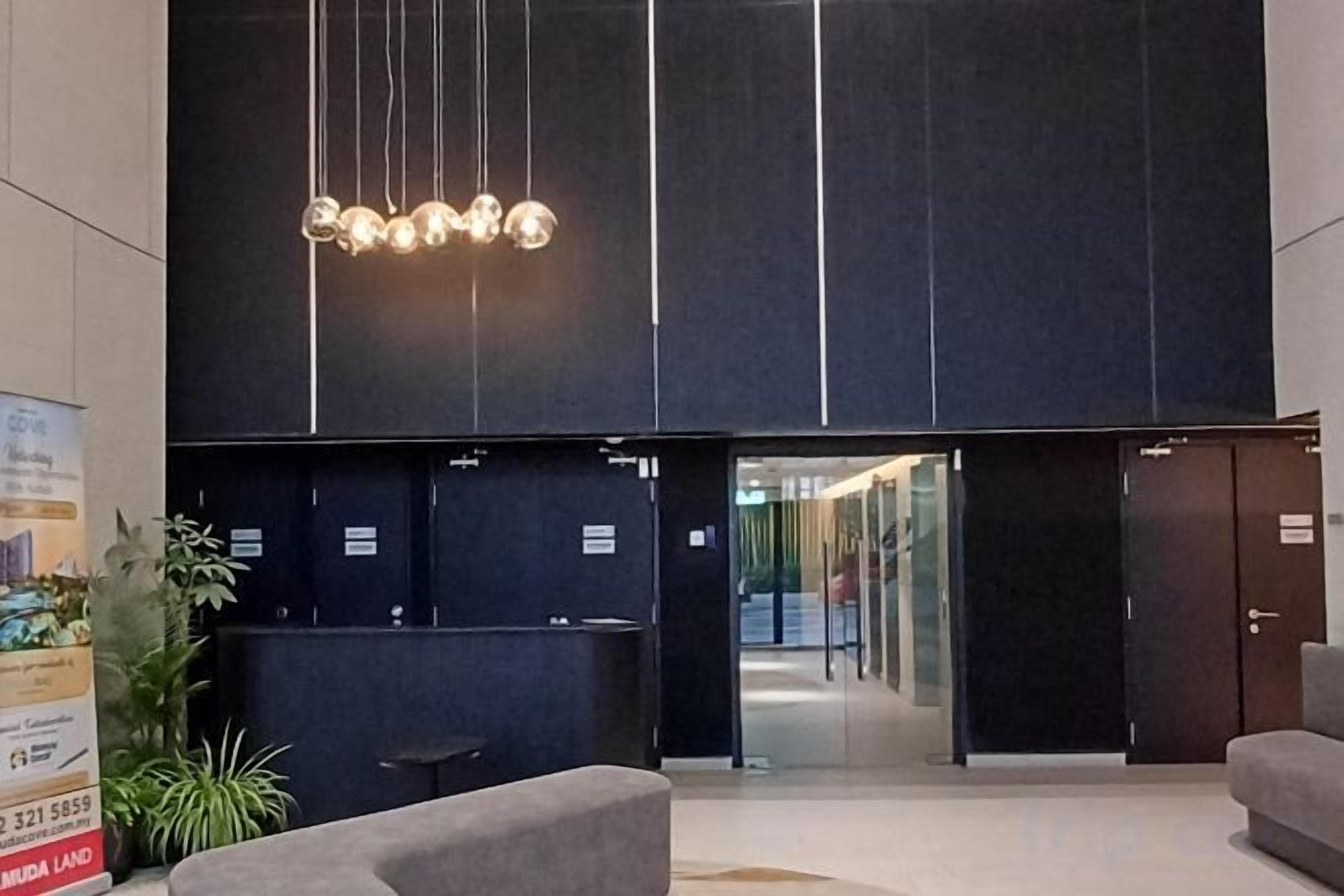 Zona de recepción con diseño moderno, que incluye un mostrador de recepción, un área de descanso y un gran letrero iluminado arriba.