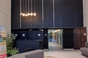 A reception area with a modern design, featuring a reception desk, a seating area, and a large illuminated sign above.