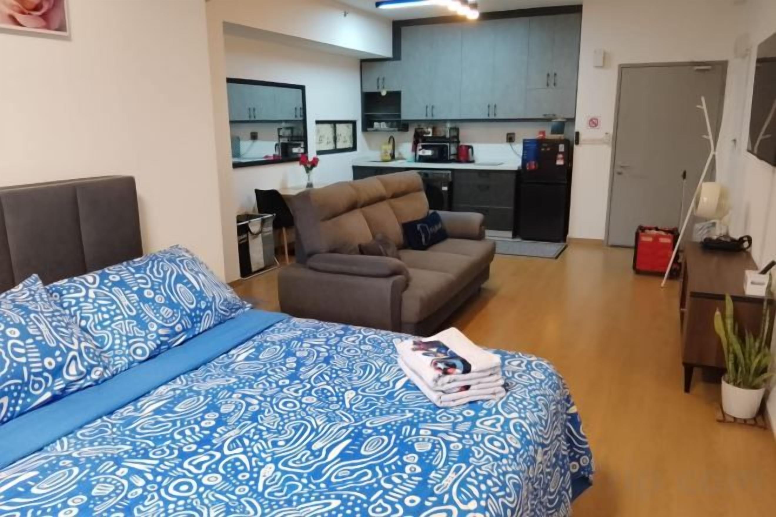 Een slaapkamer met een bed, een bank, een kitchenette en een deur.