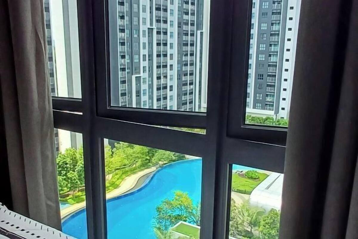 A view through a window with multiple panes, revealing a high-rise building and a landscaped area with a pool.